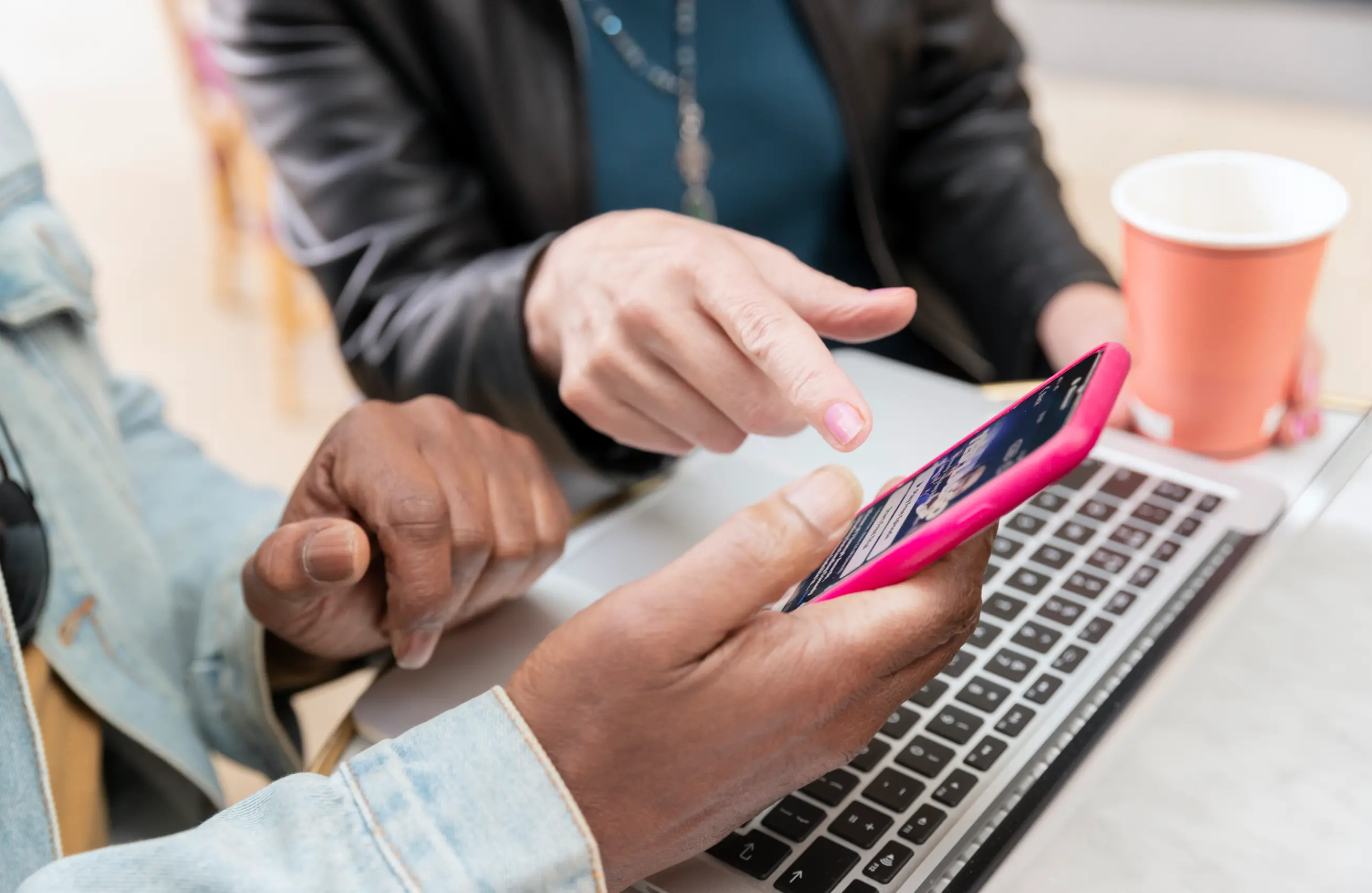 Duas pessoas sentadas com smartphone sobre laptop vendo como funciona o Pix