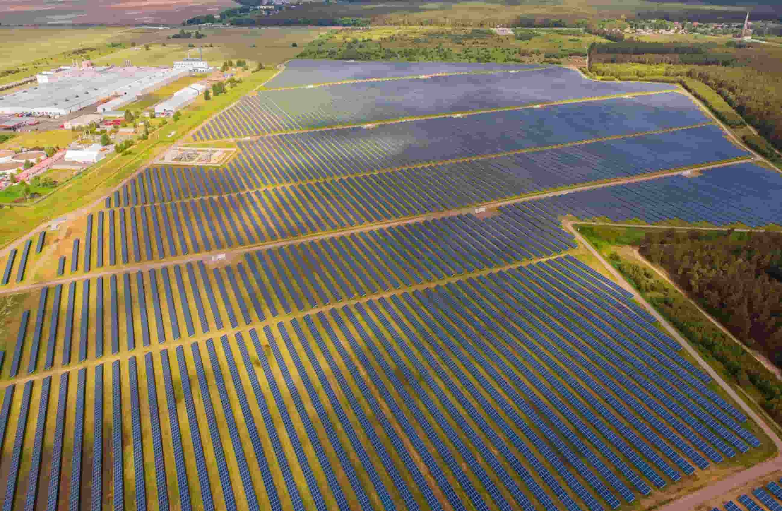 Um campo aberto de gramado com milhares de placas de energia solar com vista aérea de drone.