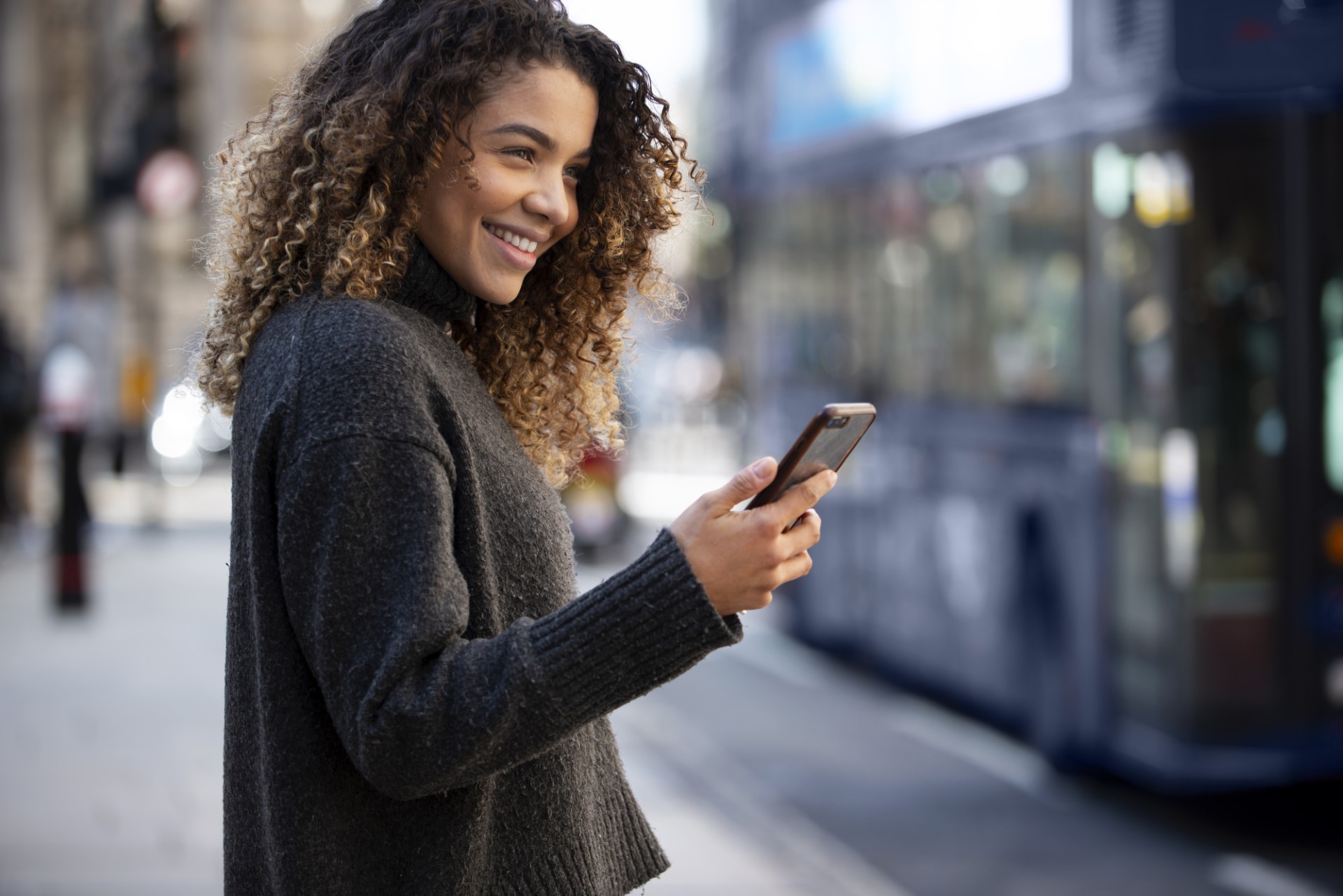 Uma mulher utilizando um smartphone em um local público.