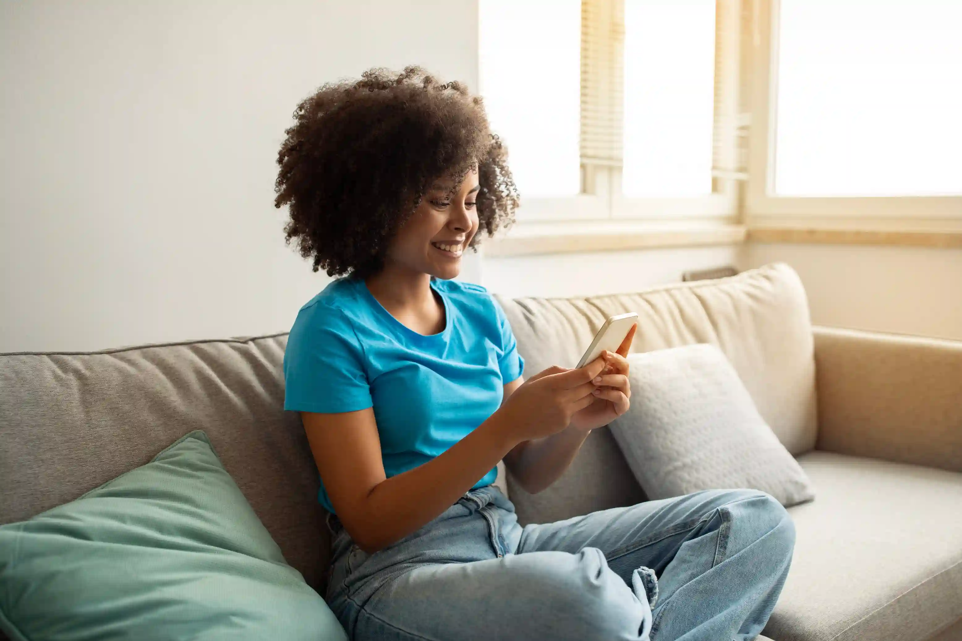 mulher sentada no sofá com celular na mão
