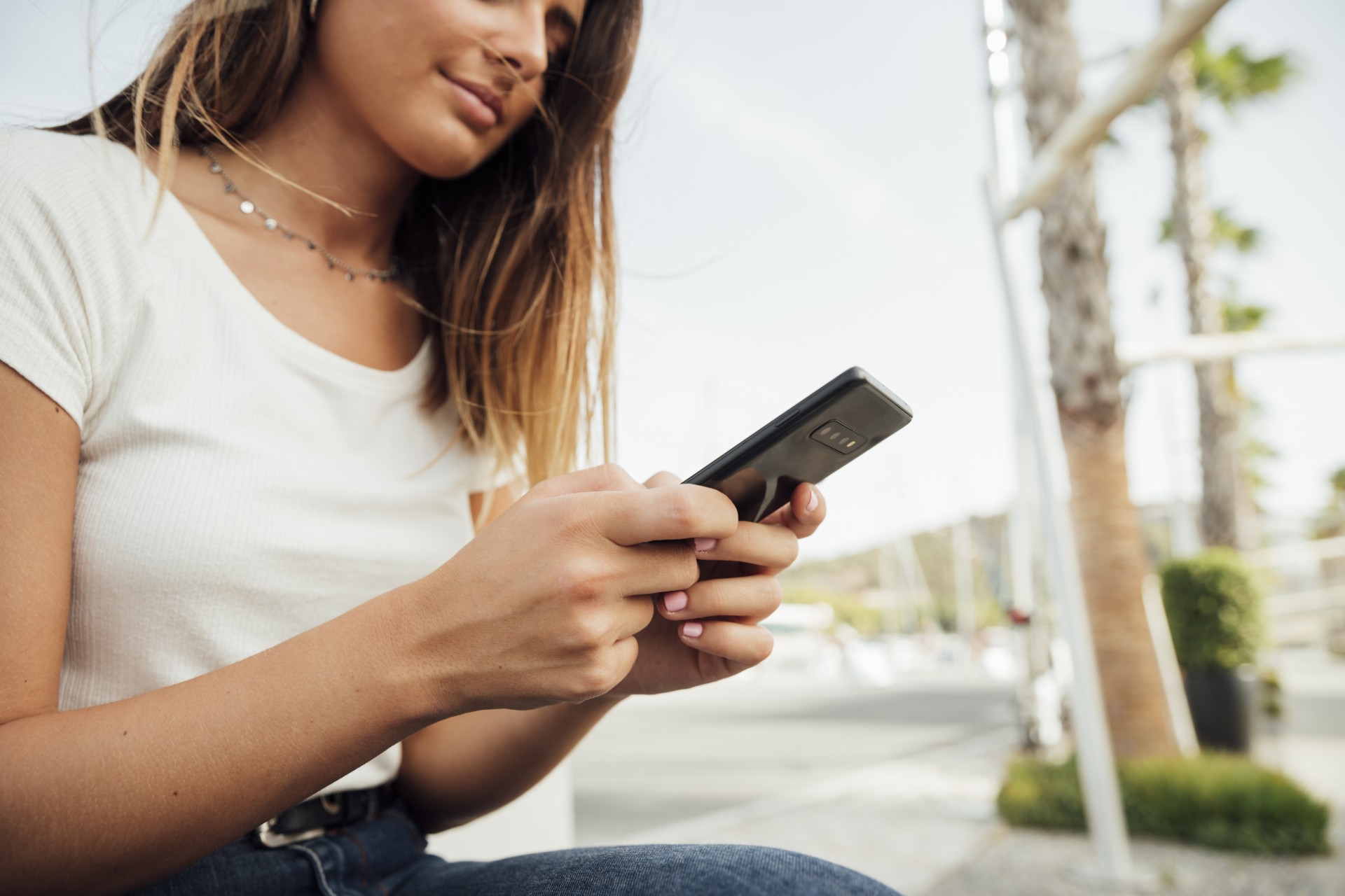 Uma mulher utilizando um smartphone em um local público.
