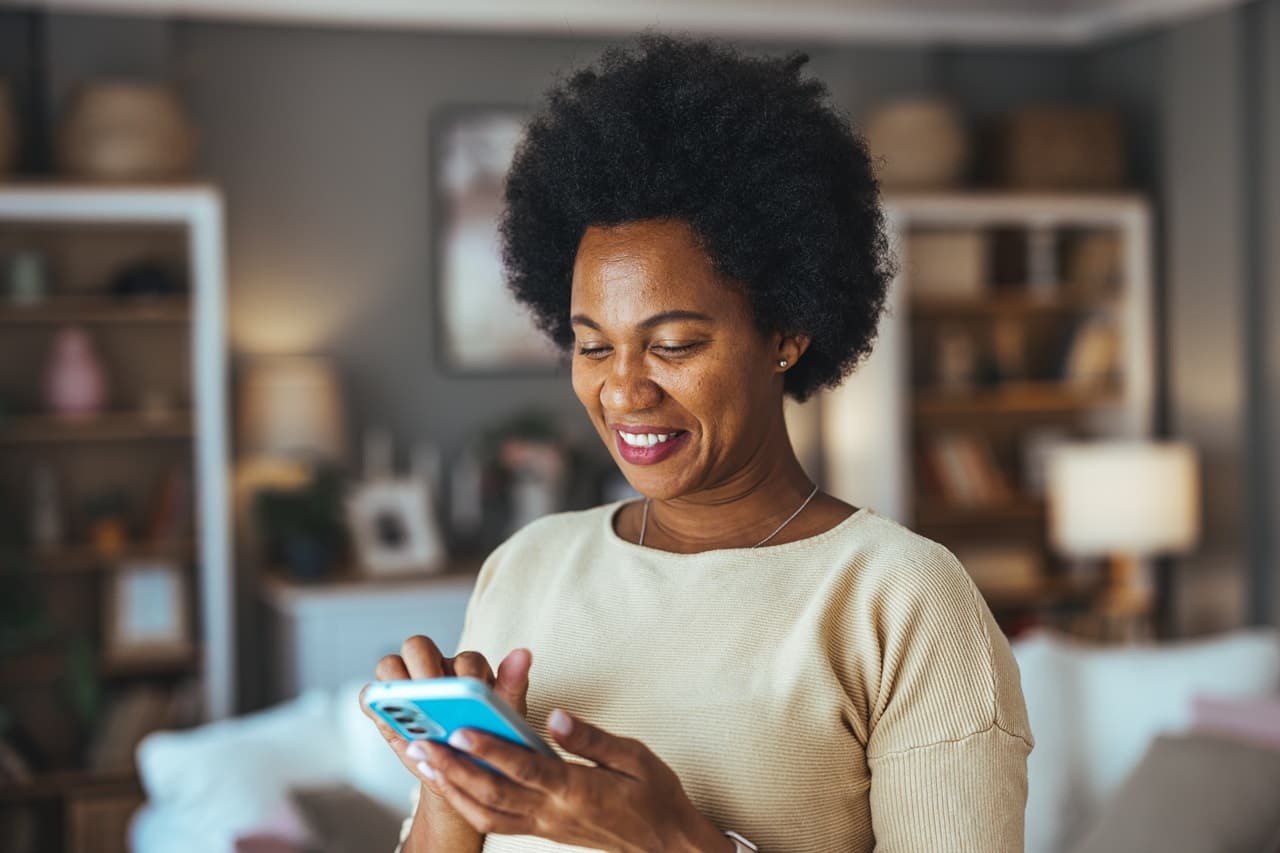Mulher sorrindo, segurando o celular.