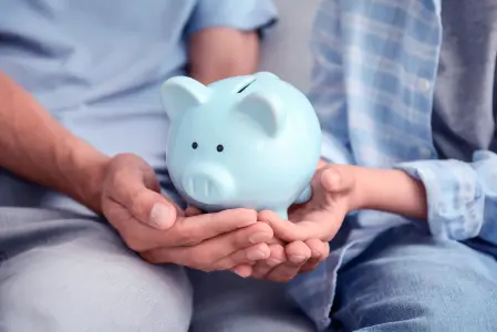 Duas pessoas segurando um cofre de porquinho de porcelana azul.