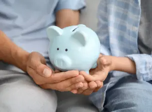 Duas pessoas segurando um cofre de porquinho de porcelana azul.