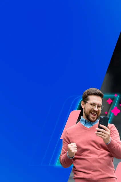 Homem branco olhando para a tela de um celular com uma expressão alegre e fazendo gesto de comemoração com uma das mãos.