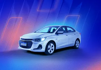 Na imagem, temos um carro sedan branco com faróis acesos. Ao fundo, temos luzes rosa e azul claro em um fundo azul marinho.