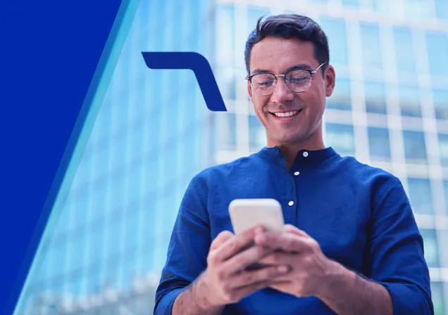 Um homem sorrindo está segurando um celular com as duas mãos e olhando para a tela