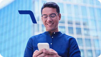 Um homem sorrindo está segurando um celular com as duas mãos e olhando para a tela