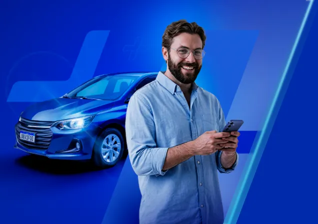 Homem branco em pé, vestindo uma camisa de botão azul-clara, com o celular na mão. Ao fundo, um carro azul.