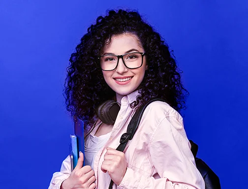 A imagem tem um fundo azul escuro. No centro da imagem há uma mulher branca, de cabelo preto cacheado. Ela usa um óculos de grau preto, está com um headphone preto em volta do pescoço, uma mochila preta nas costas, veste uma camisa rosa claro e uma camiseta branca. Com o braço direito, ela segura uma pasta e um livro azul. Já a mão esquerda está segurando a alça da mochila.