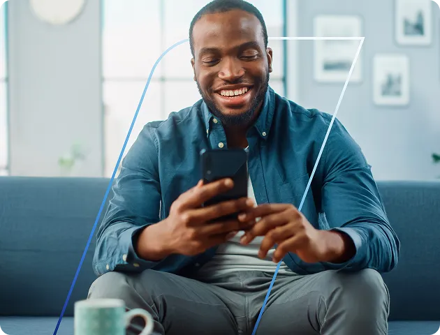 Homem sorridente sentado no sofá segurando o celular