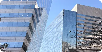 Dois prédios espelhados refletem o céu azul.