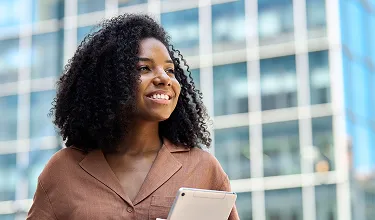 Uma mulher negra, olha para o horizonte enquanto sorri.