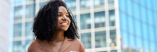 Uma mulher negra, olha para o horizonte enquanto sorri.