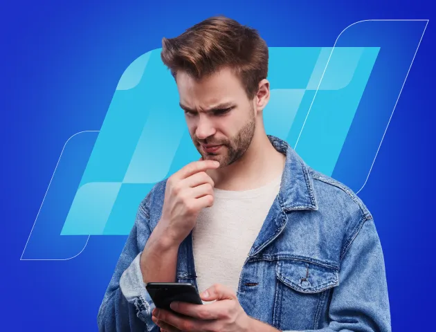 Um homem branco, de barba por fazer, olha pensativo para o celular.