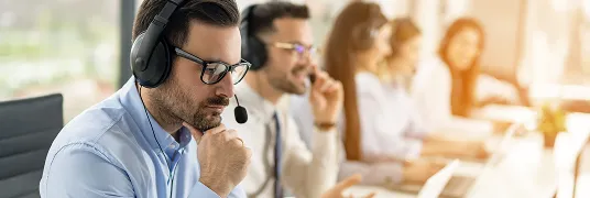 Em uma sala de atendimento, pessoas usam fones de ouvido.