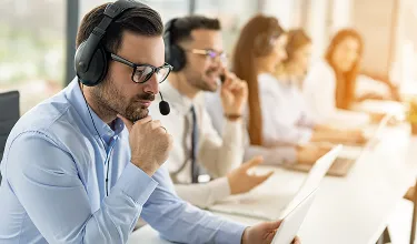 Em uma sala de atendimento, pessoas usam fones de ouvido.