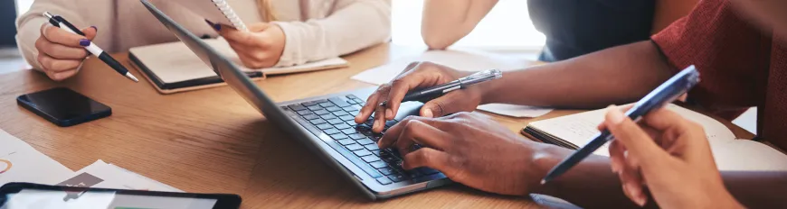 Pessoas reunidas sentadas a mesa em ambiente de trabalho.
