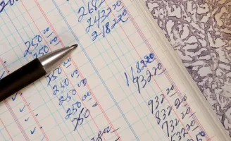 Uma caneta sobre caderno aberto com números anotados a mão.