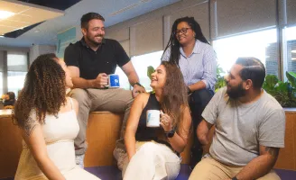 Profissionais do banco BV reunidos em local de trabalho.