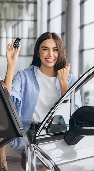Mulher sorrindo segurando a chave enquanto entra no carro