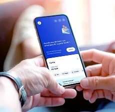 Pessoa segurando o celular com app do BV na tela de conta digital.