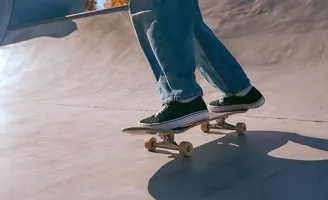 Uma pessoa de calça, andando de skate em uma pista.