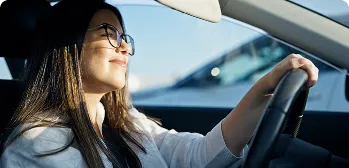 Mulher com a mão no volante do carro.