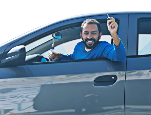 Homem sentado na posição do motorista, sorrindo com uma chave de carro na mão