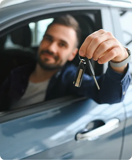 Homem dentro de um carro estende mão pela janela segurando a chave.