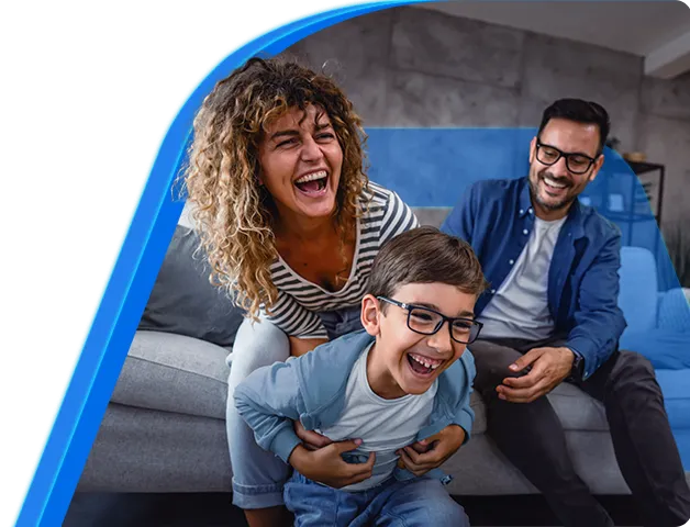 Um homem, uma mulher e uma criança felizes, sorrindo enquanto se divertem sentados no sofá da sala.