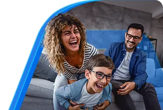 Um homem, uma mulher e uma criança felizes, sorrindo enquanto se divertem sentados no sofá da sala.