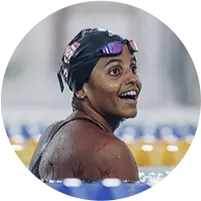 Ex-nadadora Etiene Medeiros, sorrindo, dentro de uma piscina e usando uma touca de natação e óculos de natação.