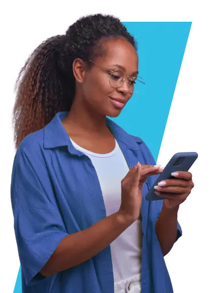 Mulher com óculos, pele negra, cabelos cacheados preso, vestindo camisa azul por cima de camiseta branca, segurando e olhando para celular e sorrindo