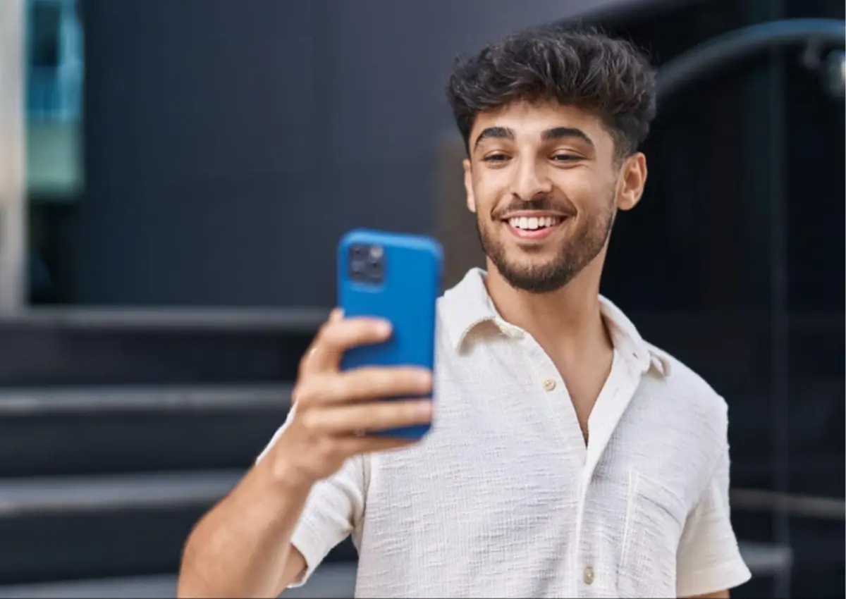 Homem sorridente segurando celular de capinha azul, vendo como funciona o Pix Open Finance.