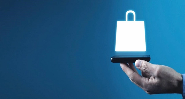 Homem segurando celular, com ícone de compra acima da tela e fundo azul.