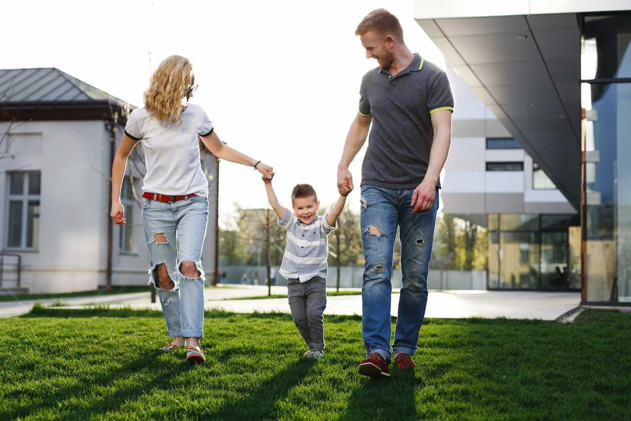 Casal com uma criança caminhando alegremente em uma área residencial, simbolizando a qualidade de vida e os benefícios da energia solar para o futuro.