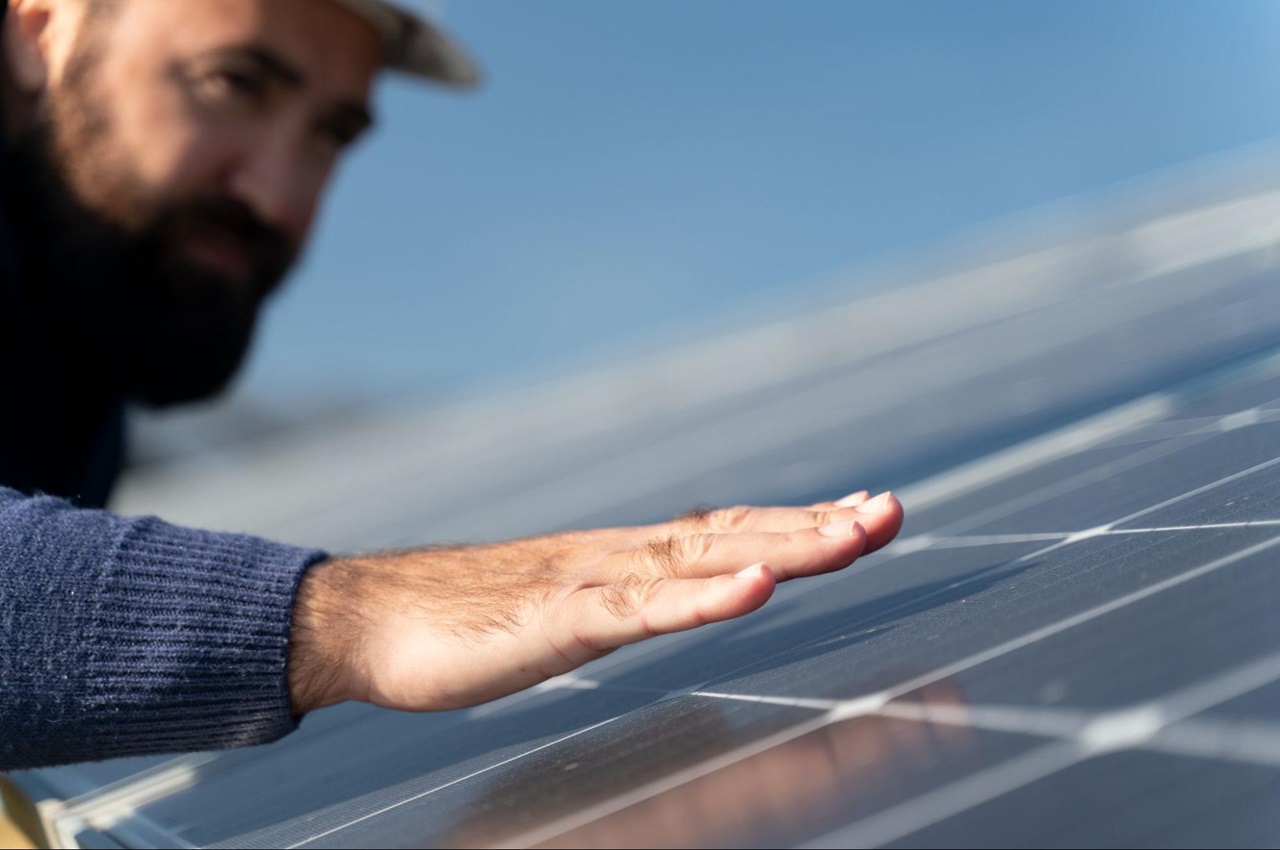 Homem inspecionando painel solar no telhado de uma casa ao ar livre.