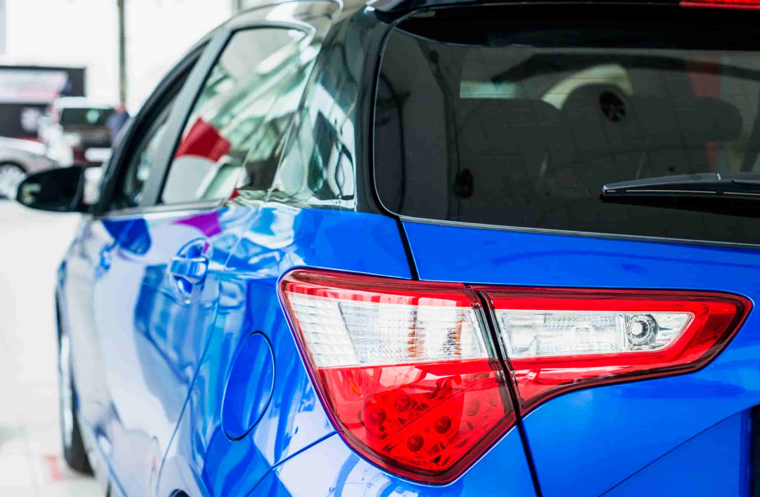 Traseira de carro azul e preto, que está dentro de uma concessionária. A imagem representa os carros que custam menos de 50 mil reais.