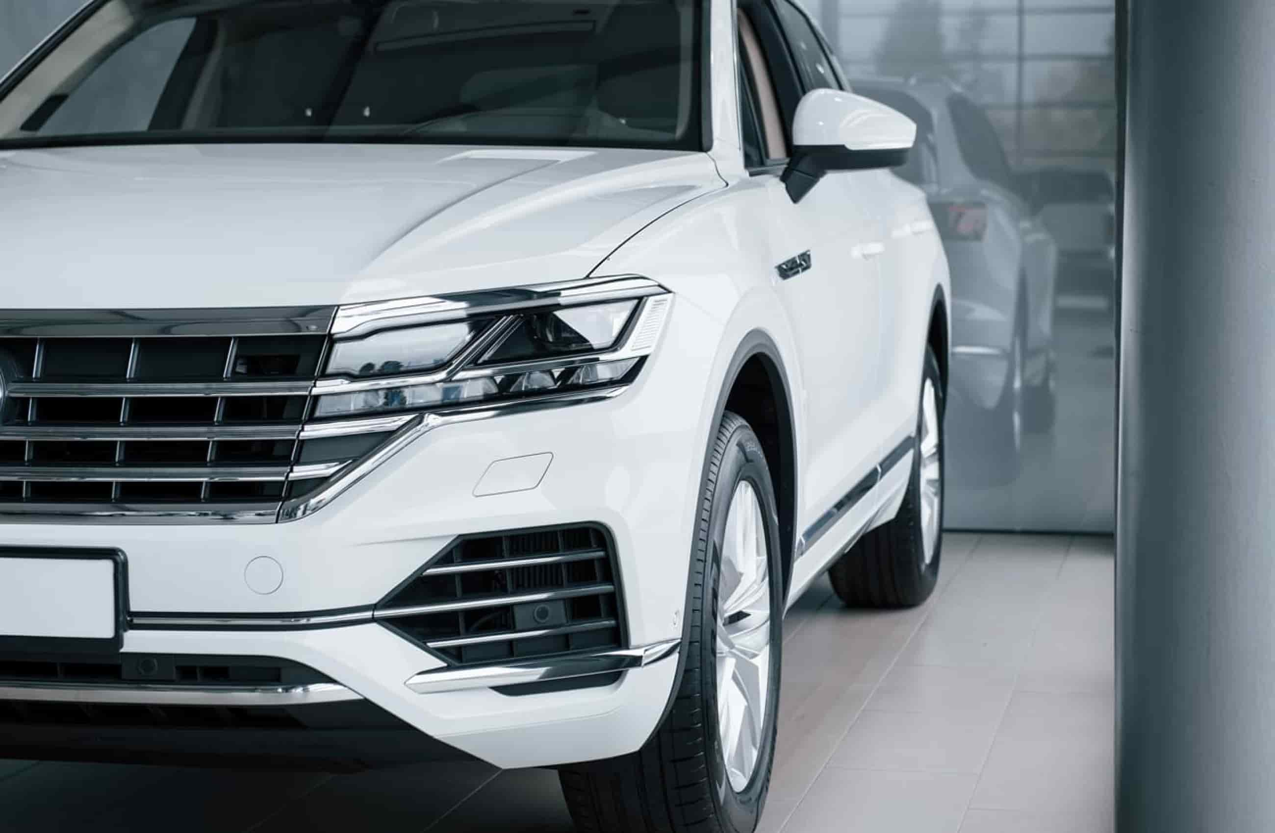 Carro branco estacionado dentro de uma concessionária, representado o Financiamento de Veículos BV.