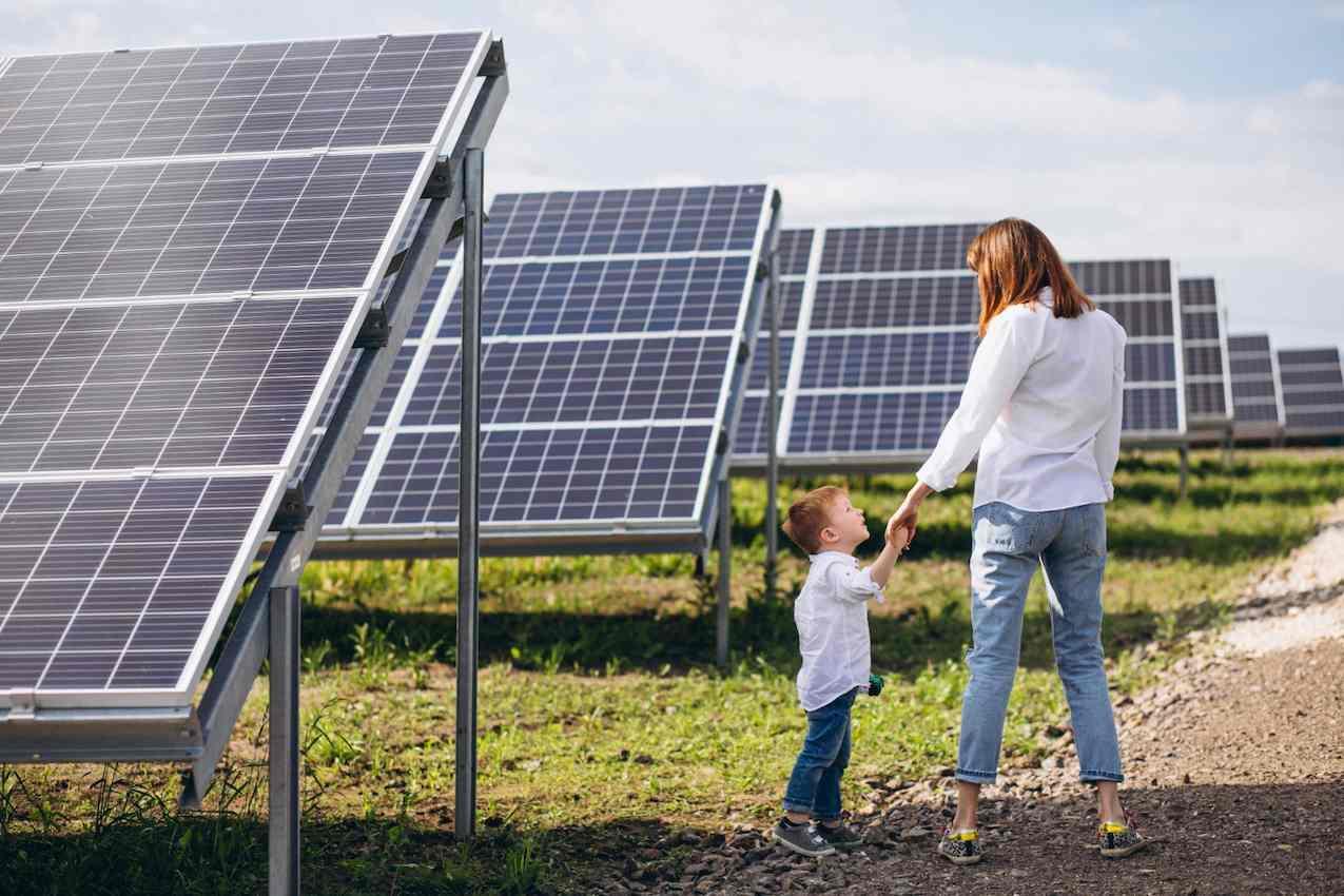 Mãe e filho observando painéis solares, simbolizando como a energia solar por assinatura impacta positivamente a vida das famílias e o meio ambiente.