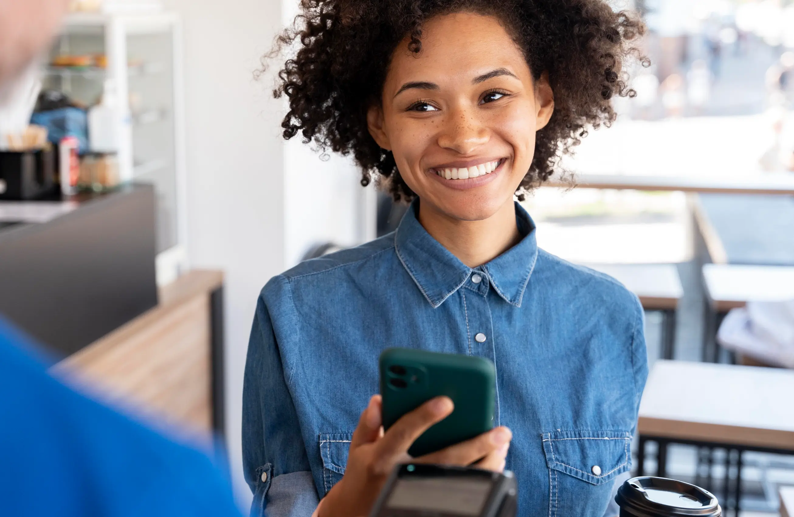 Uma mulher sorrindo enquanto segura um smartphone.