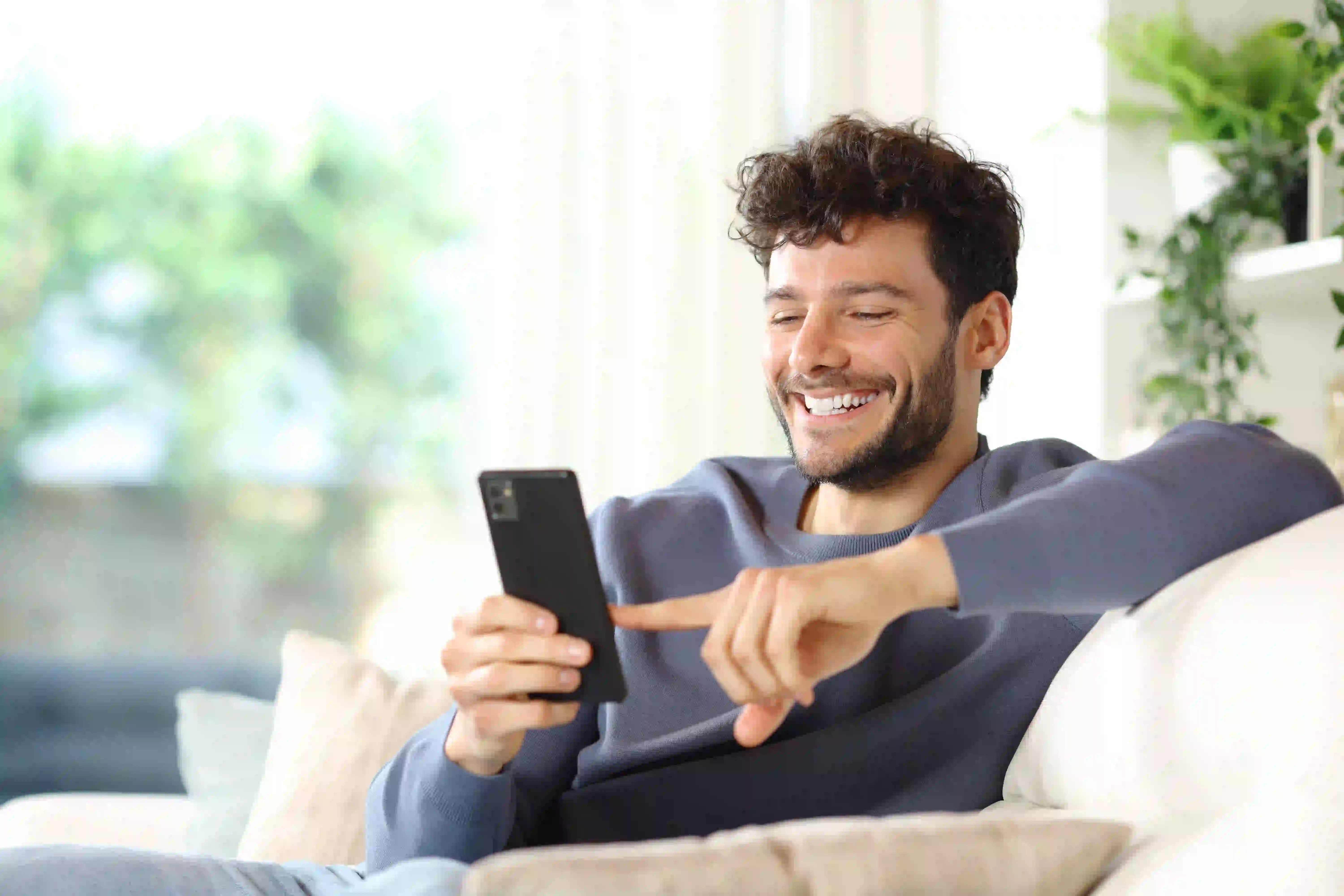 homem sentado no sofá mexendo no celular