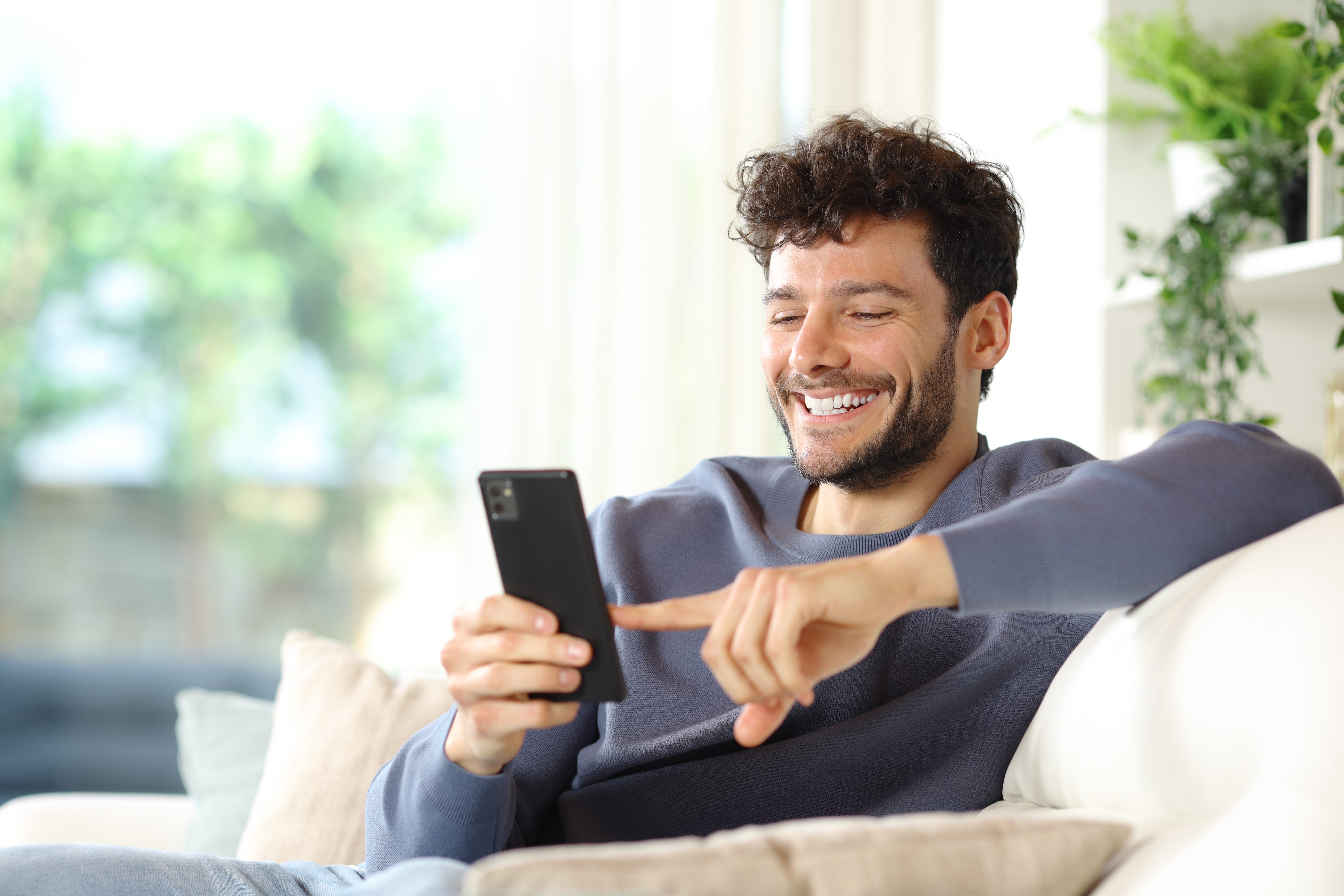 homem sentado no sofá mexendo no celular