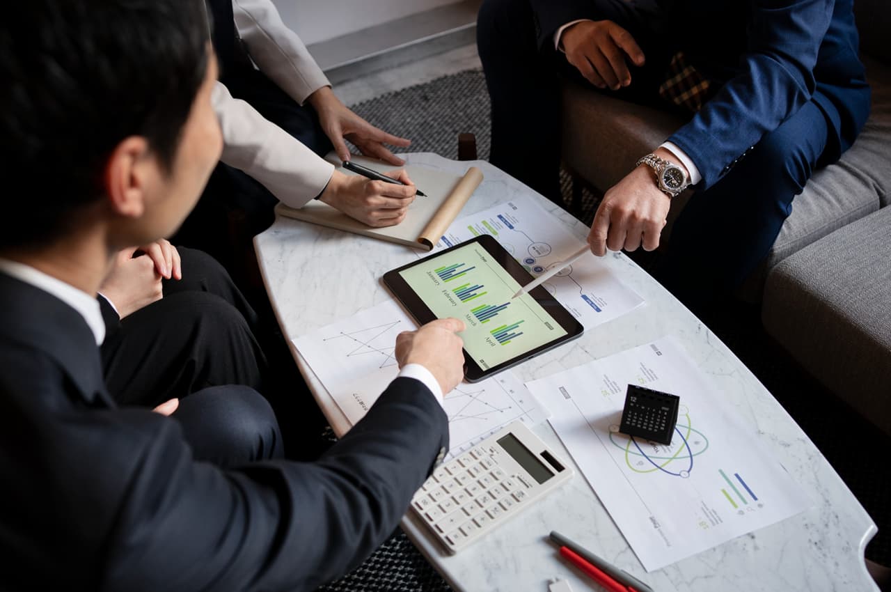 Executivos analisam gráficos em tablet e relatórios, discutindo governança e compliance corporativa.
