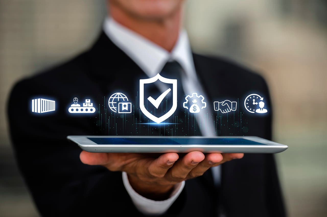 Homem de terno segurando tablet com ícone de escudo e processos empresariais para representar a cultura da segurança.