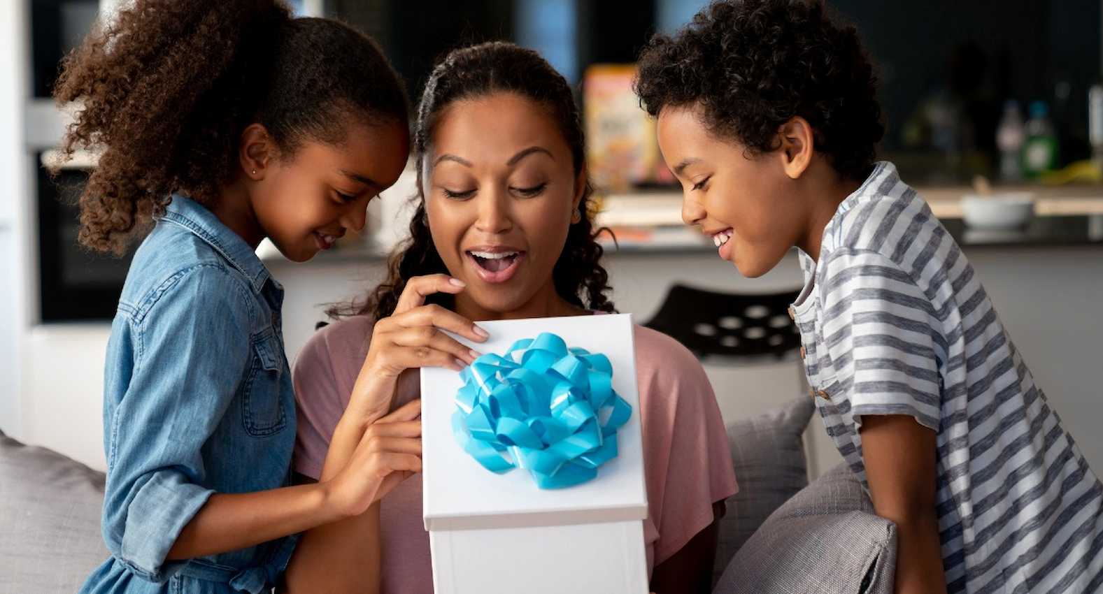 A imagem mostra dois filhos entregando um presente para sua mãe.