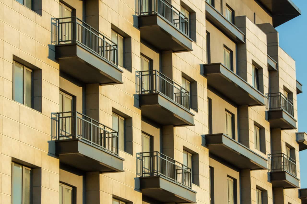 Edifício moderno com varandas e janelas, em tom claro.