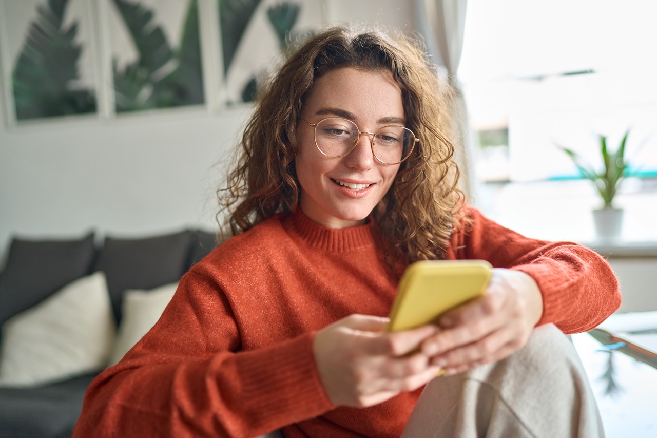 Mulher sentado no sofá segurando um celular na mão