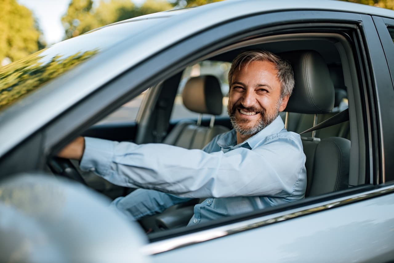 Homem sorrindo dentro do carro